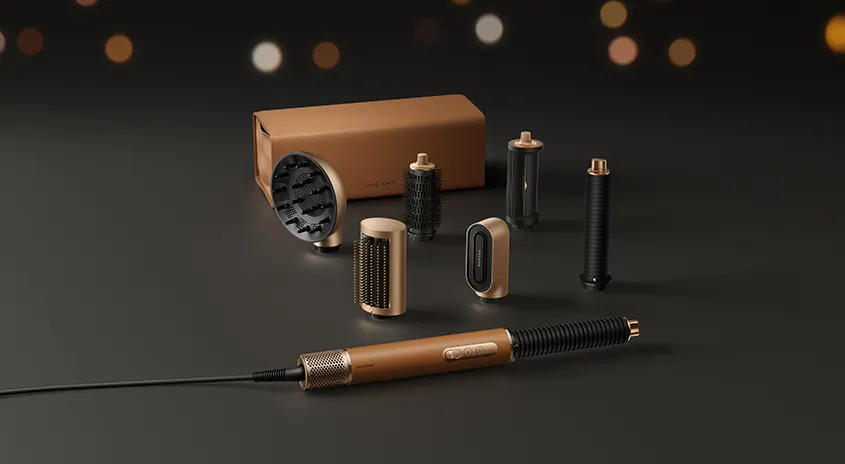 Multifunktionales Haarstyling-Set in Braun und Gold mit verschiedenen Aufsätzen in brauner Verpackung auf dunklem Hintergrund mit bokeh-Lichtern.