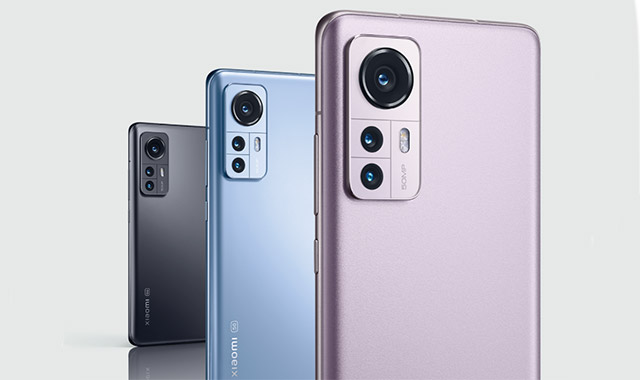 Drei Smartphones in Grau, Blau und Lila mit rechteckigen Kameramodulen auf der Rückseite vor einem weißen Hintergrund.