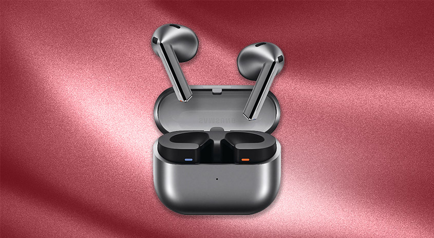 Silberne Ohrhörer liegen in einem grauen Ladeetui mit offenem Deckel vor einem rosa Hintergrund.