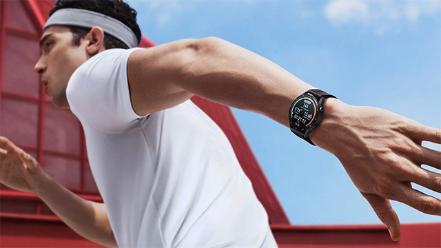 Ein Mann mit weißem Shirt und Stirnband rennt. Eine schwarze Smartwatch zeigt Daten an. Im Hintergrund sind rote Elemente und blauer Himmel.