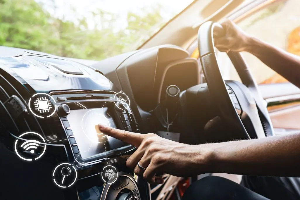 Person bedient Touchscreen im Auto, mit digitalen Symbolen fuer Technik und Konnektivitaet