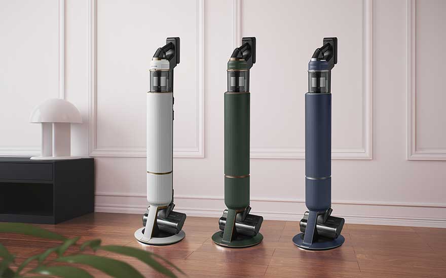 Trois aspirateurs balais haut de gamme sur socle rond, en blanc, vert et bleu, illustrent des couleurs chic pour intérieurs modernes.