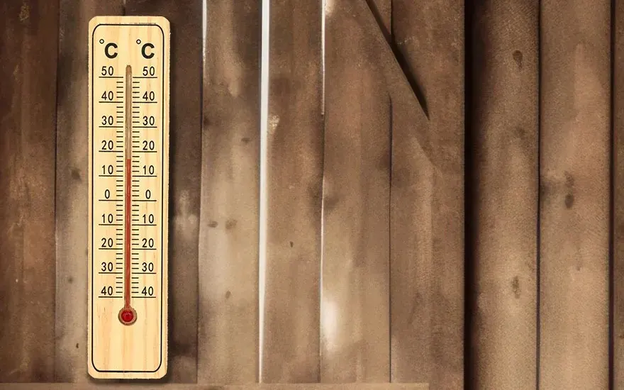 A thermometer indicates 40 degrees Celsius on a wooden wall. The wall consists of vertical wooden planks.