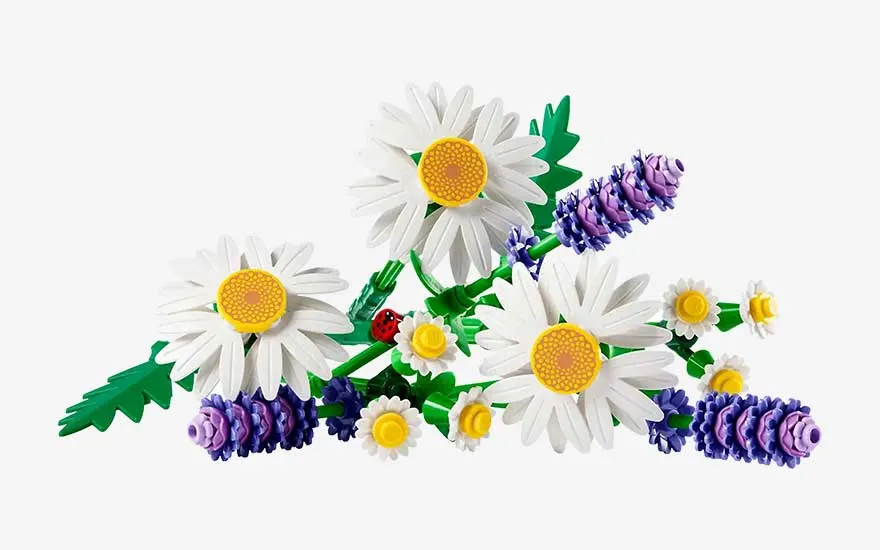 A cheerful bouquet of white daisies and purple lavender, built from bricks, rests playfully against a plain white background.