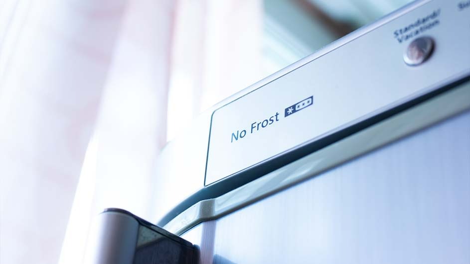 Detail van een witte koelkast met de tekst "No Frost" en knop "Standaard/Vakantie".