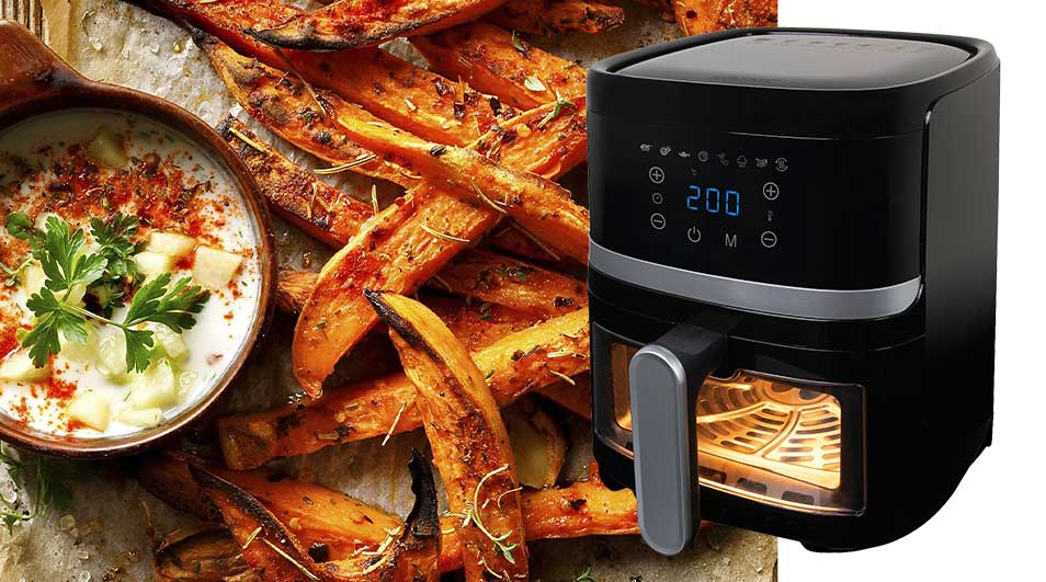Op een foto staan zoete aardappelfrietjes naast een zwarte airfryer en een kom met witte saus en kruiden.