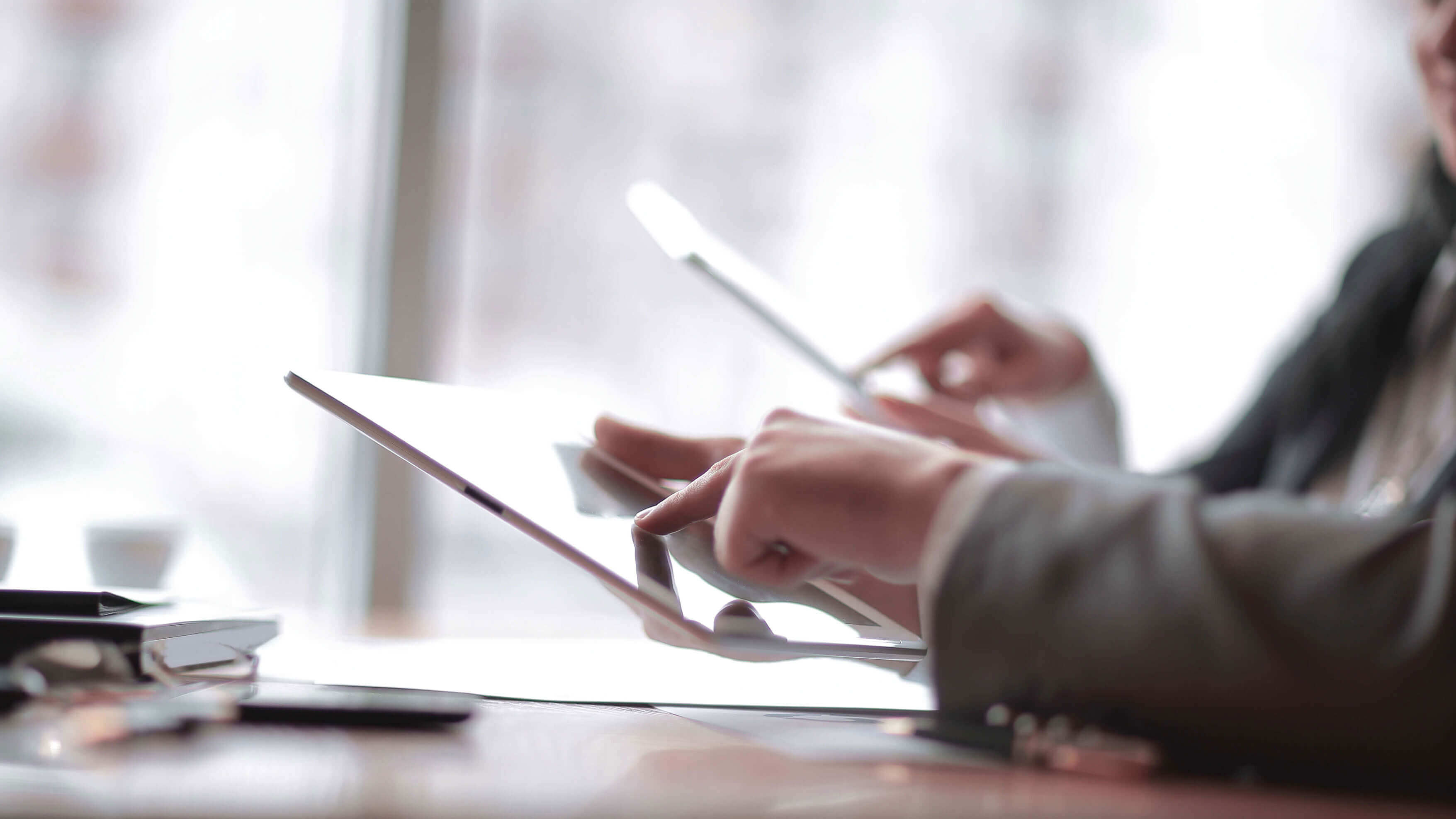 Person holds a Kobo eReader with stylus, highlighting text. Reader rests on a green surface. A hand wears a ring.