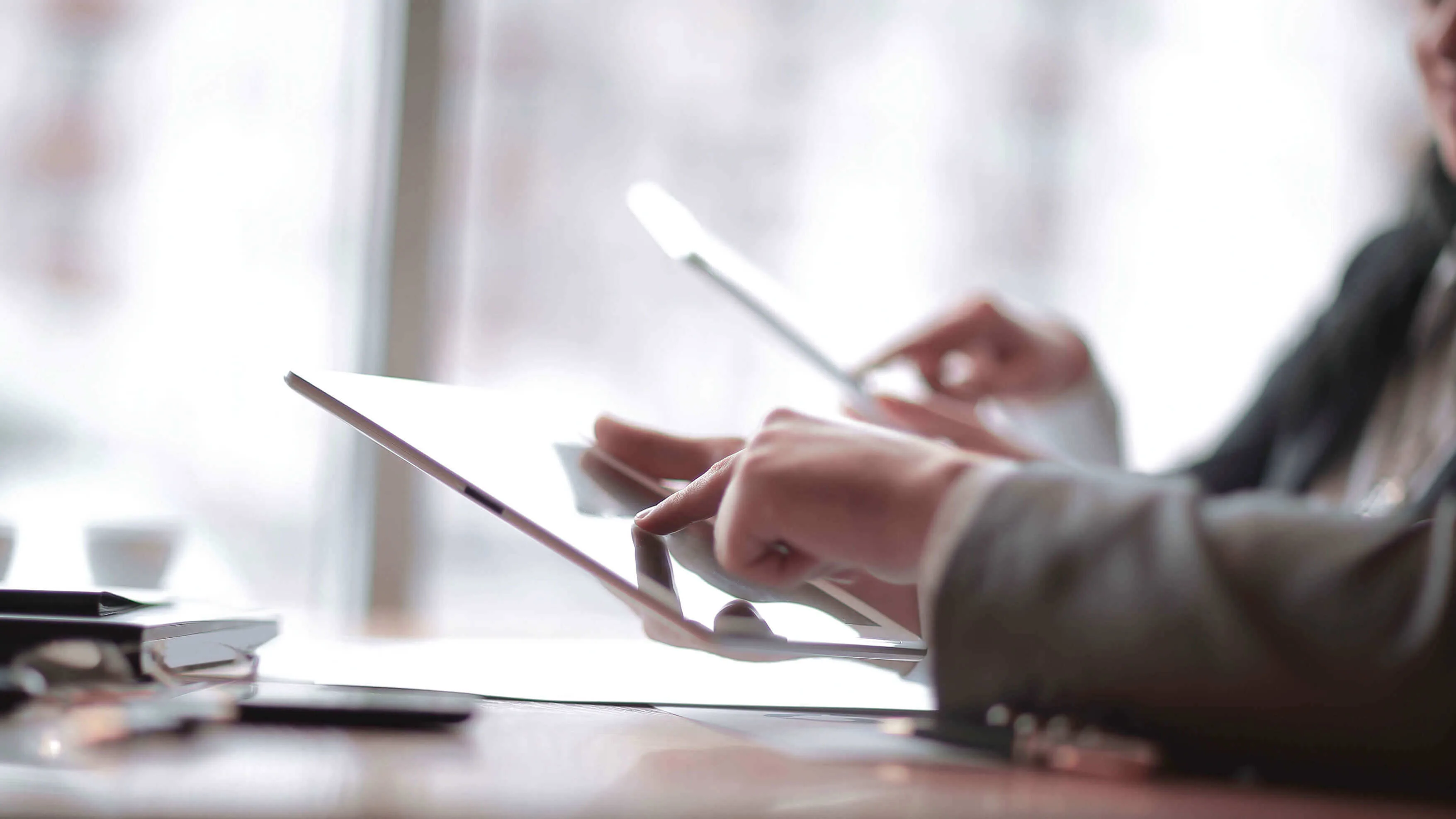 Une personne tient un lecteur électronique Kobo avec un stylet et surligne un texte. Le lecteur est posé sur une surface verte. Une main porte une bague.