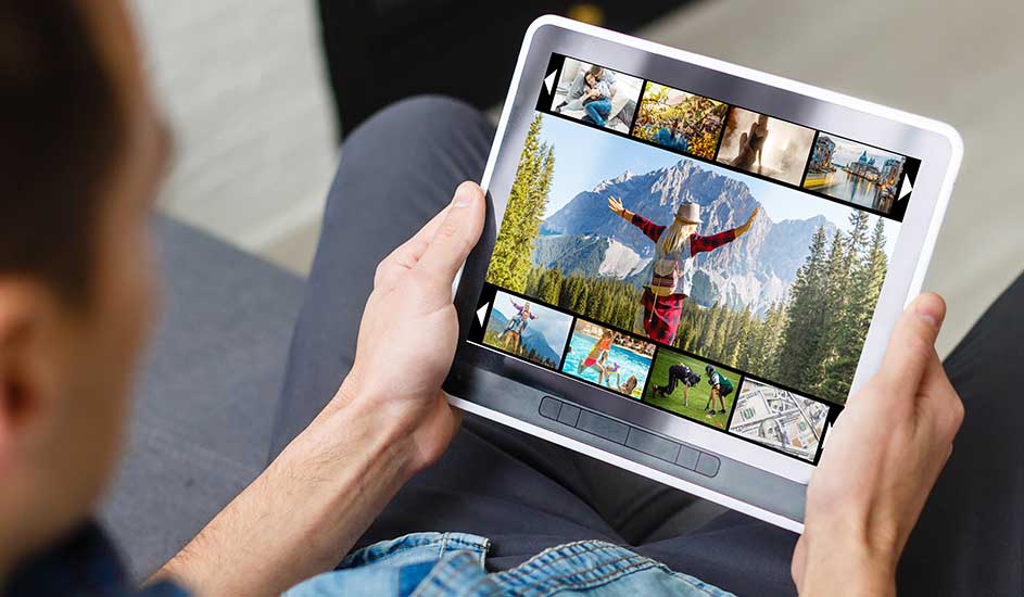 Tablet met fotoserie in handen. Foto's tonen landschappen, avonturen en stadsgezichten. De achtergrond is vaag en zacht.
