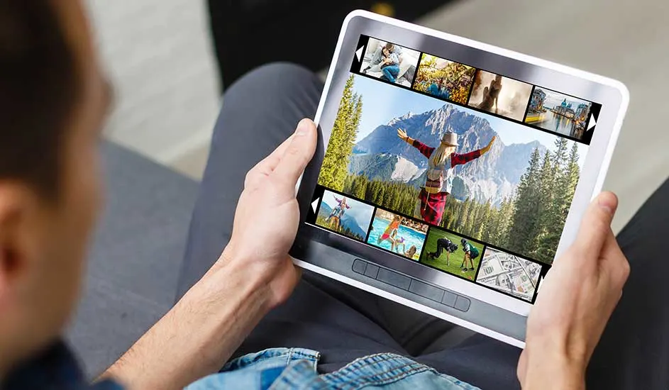 Une tablette blanche affiche des images de voyage. Des paysages montagneux et des scènes de nature sont visibles à l'écran.