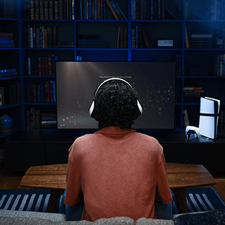 Personne portant un casque assise devant un grand écran dans une pièce sombre.