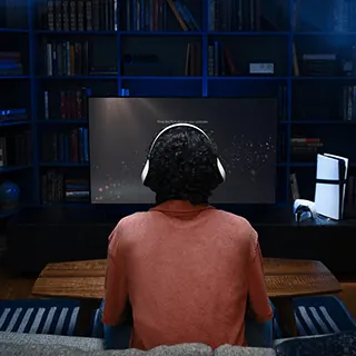 Personne portant un casque assise devant un grand écran dans une pièce sombre.