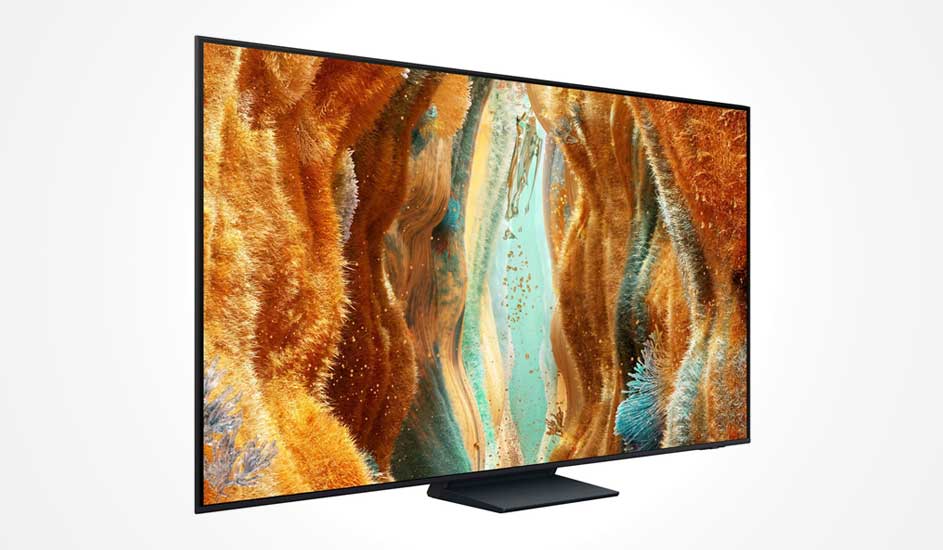 Een Samsung televisie met dun zwart frame staat op een brede voet en toont een abstract beeld met oranje, goud en blauwe tinten op het scherm.