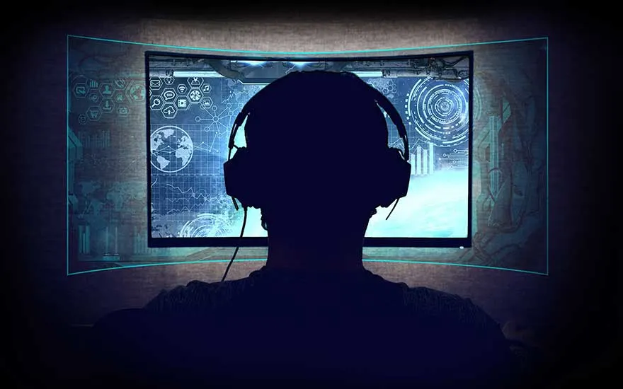 Een donkere foto van een computerscherm dat blauwe grafieken en symbolen weergeeft, met een hoofdtelefoon ervoor.