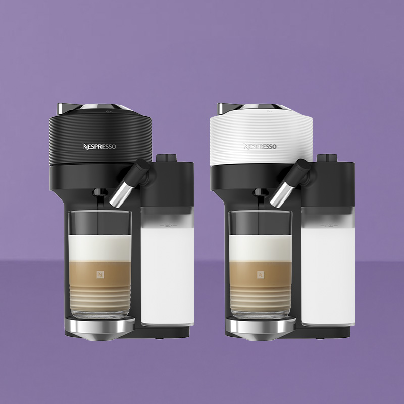 Twee Nespresso-koffiemachines met geïntegreerde melkopschuimers op een paarse achtergrond, één zwart en één wit, elk met een gelaagde melk-koffiedrank in een glas.