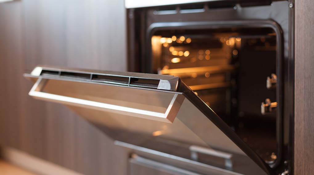 An open oven with a lit interior. The oven door is ajar, showing the inside elements.