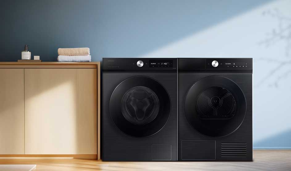 Twee zwarte wasmachines naast een lichte kast met handdoeken; blauwe muur met zonlichtschuine schaduw, rustige minimalistische washoek.