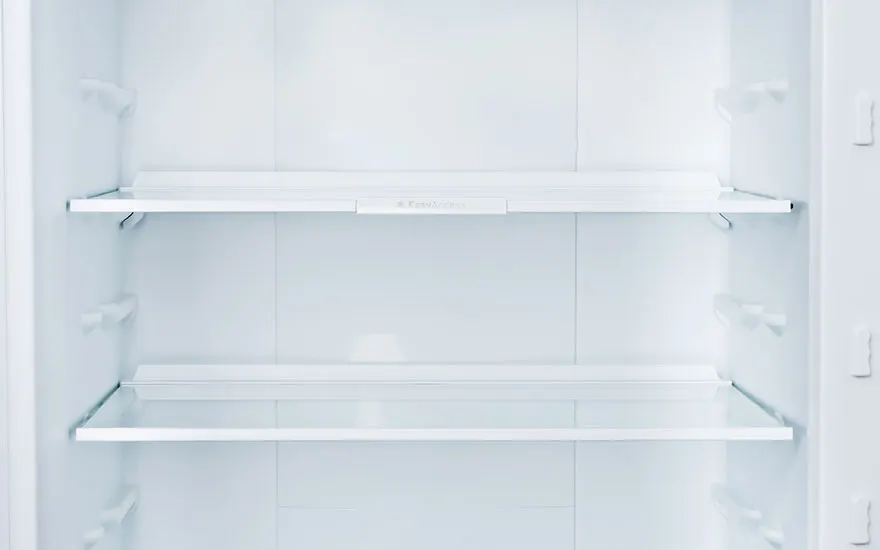 An empty, all-white refrigerator with two glass shelves and multiple shelf slots is shown.