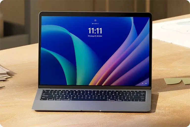 Een open laptop op een houten bureau toont een blauw scherm met abstracte vormen en de tijd 11:11.