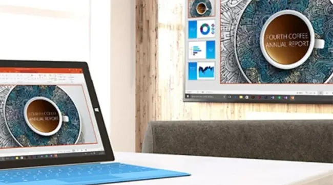 Een blauwe laptop en een monitor tonen een rapport met een kop koffie op een wit bureau.