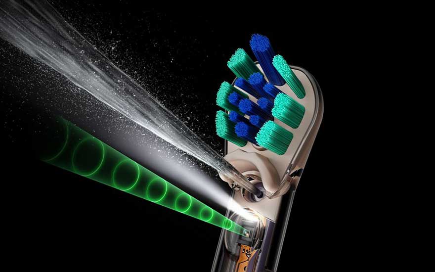 Een doorsnede van een elektrische tandenborstel toont kleurrijke borstelharen, een waterstraal en groene lichtcirkels rond het mondstuk.