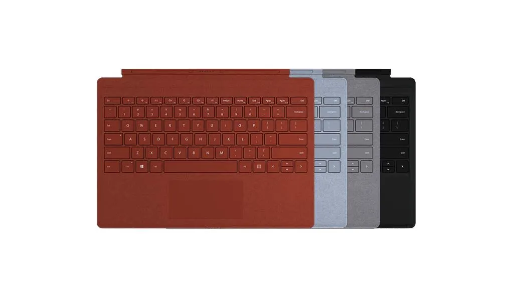 Quatre claviers Surface de couleurs différentes (rouge, bleu clair, gris, noir) sur fond blanc.