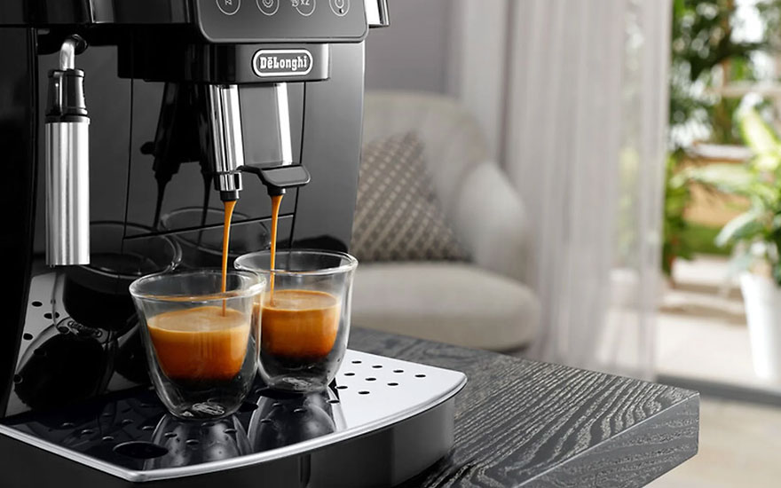 Een zwarte DeLonghi-espressomachine schenkt koffie in twee glazen. De machine staat op een donker houten oppervlak.