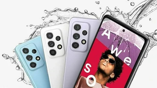 Drie Samsung telefoons in blauw, wit en paars liggen onder opspattend water. Het scherm toont tekst op een rode en paarse achtergrond.