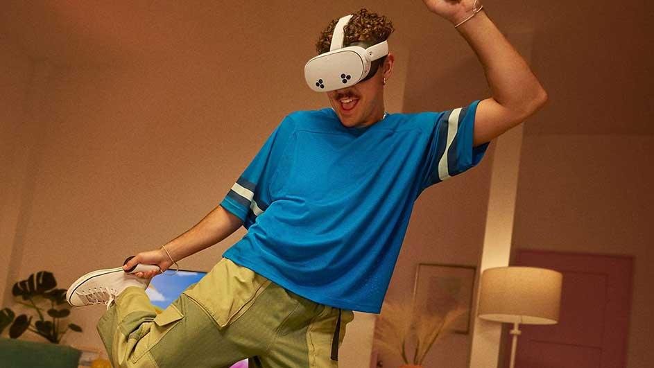 Casque VR blanc en avant-plan, t-shirt bleu, pantalon kaki. Lampe beige et plante verte en arrière-plan.