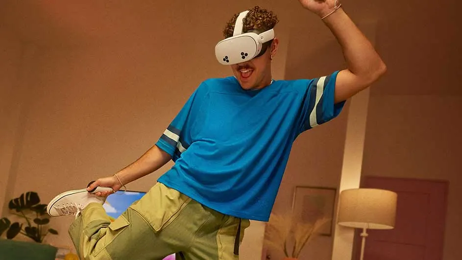 Een persoon met een blauw shirt en een VR-bril houdt een witte schoen vast in een woonkamer met een lamp.