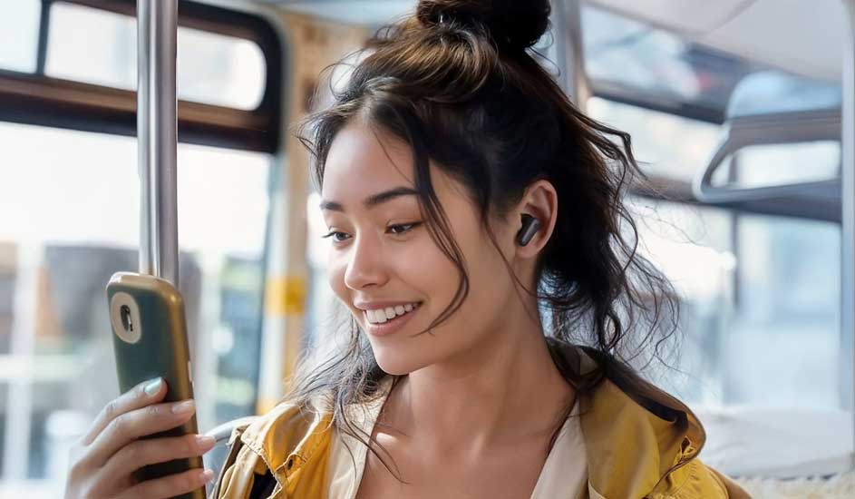 Een mobiele telefoon wordt in een bus vastgehouden, met een oortje in het oor en een gele jas.