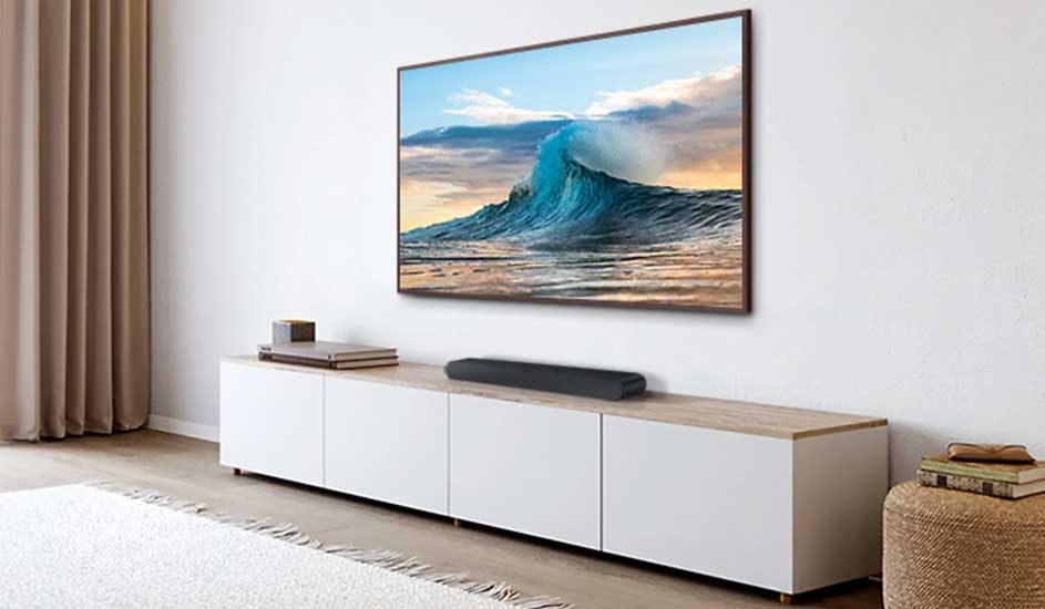 Een Samsung televisie toont een golf op het scherm, met daaronder een Samsung soundbar op een wit tv-meubel in een modern ingerichte woonkamer.