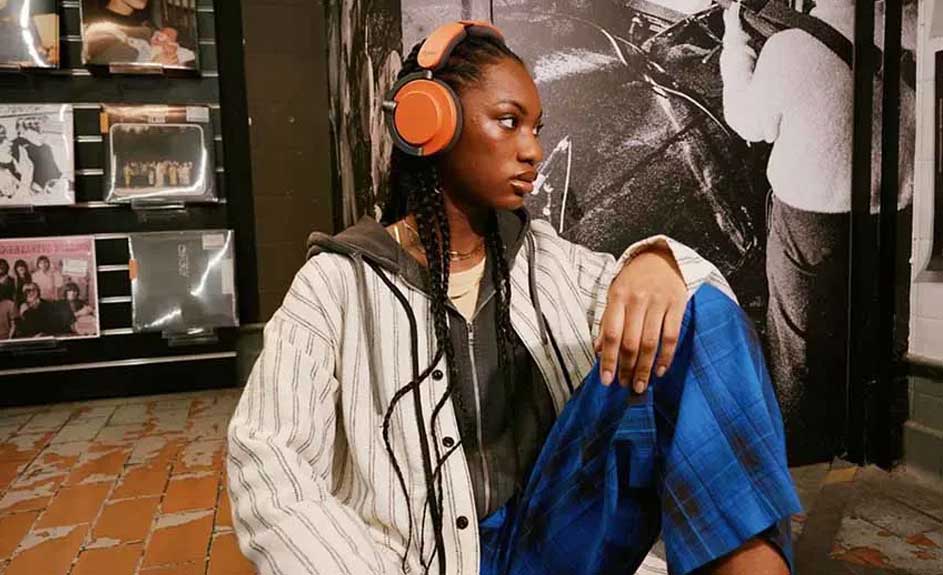 Een oranje koptelefoon ligt op een bakstenen vloer met platen op de achtergrond.