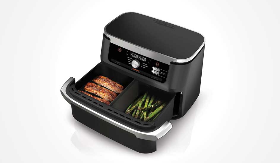 Een zwarte Ninja airfryer met twee lades, links zalm en rechts asperges, staat open op een witte achtergrond.