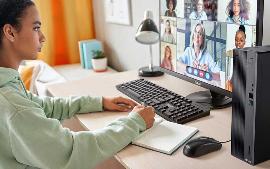 Een vrouw werkt thuis aan een computer terwijl ze deelneemt aan een videogesprek met meerdere deelnemers op haar grote monitor.