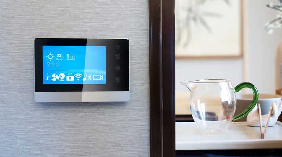 Een digitaal scherm hangt aan de muur, met een blauw display dat de tijd en temperatuur toont. Naast het scherm staat een glazen kan.