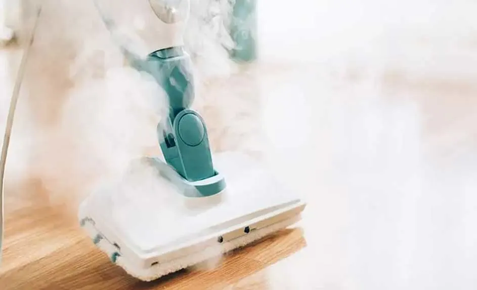 Un nettoyeur vapeur blanc et turquoise nettoie un parquet. De la vapeur s'échappe de l'appareil.