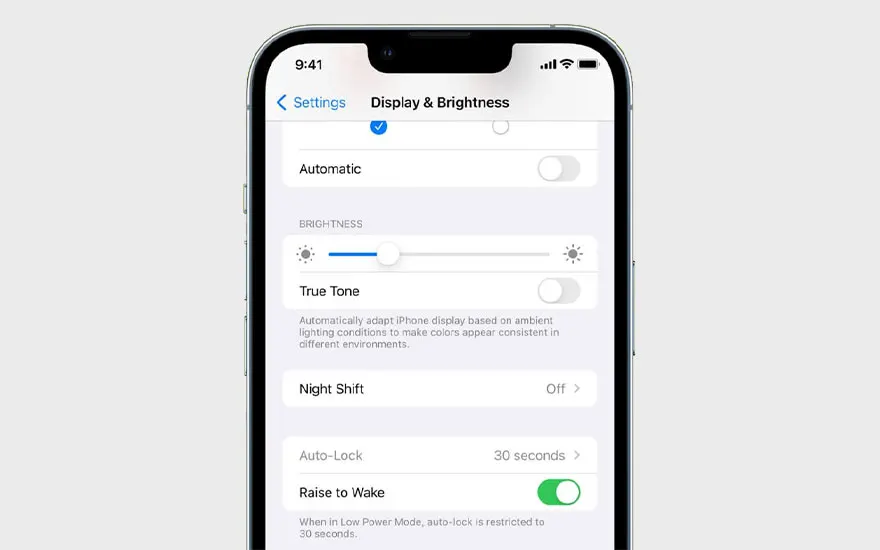 Een iPhone scherm toont 'Display & Helderheid' instellingen met opties zoals Automatisch, Helderheid, True Tone, Night Shift en Auto-Lock.