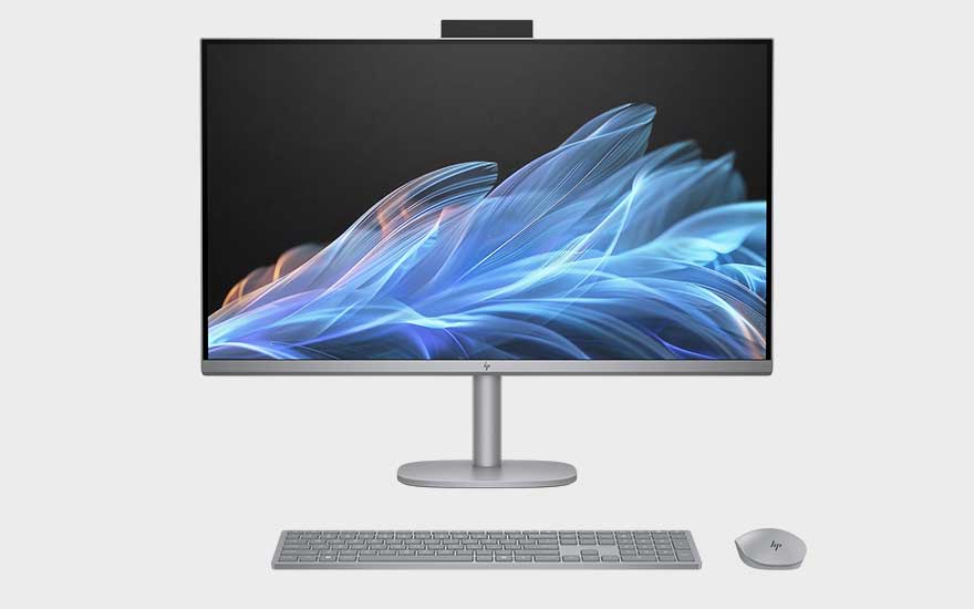Un ordinateur tout-en-un HP moderne avec webcam, clavier et souris argentés affiche des vagues abstraites bleues.
