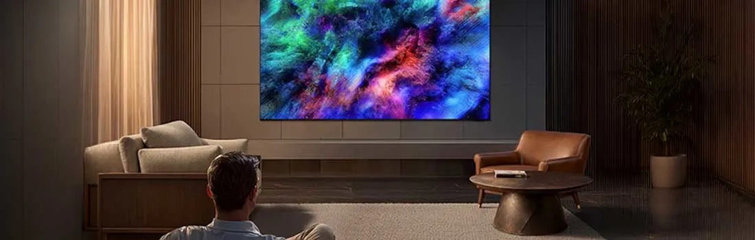 Een man kijkt in een stijlvolle woonkamer naar een grote tv met kleurrijke abstracte beelden en warme sfeerverlichting.