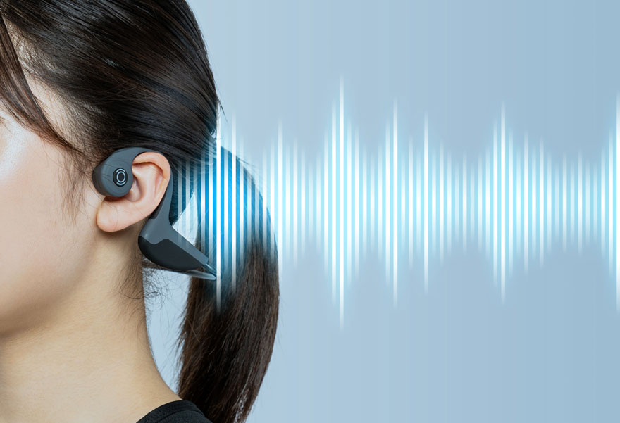 Oreillette noire sur une oreille avec des ondes sonores bleues sur un fond bleu clair.