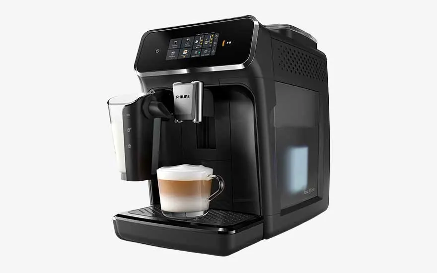 A black Philips automatic espresso machine with a touchscreen prepares a creamy milk coffee in a clear glass cup.