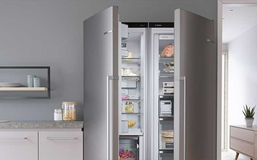 Un grand réfrigérateur en acier inoxydable à deux portes est ouvert, révélant des étagères remplies de nourriture dans une cuisine moderne.