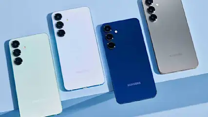 Vier smartphones in verschillende kleuren liggen naast elkaar, met de achterkant en hun drie cameras zichtbaar tegen een blauwe achtergrond.