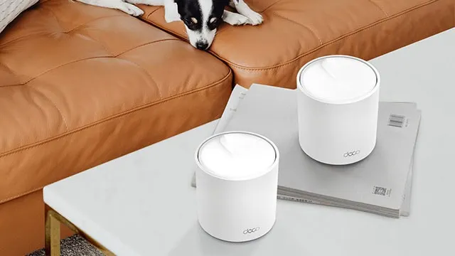 Twee witte cilinders op een tafel naast een bruine bank. Een stapel papier ligt onder de rechter cilinder.