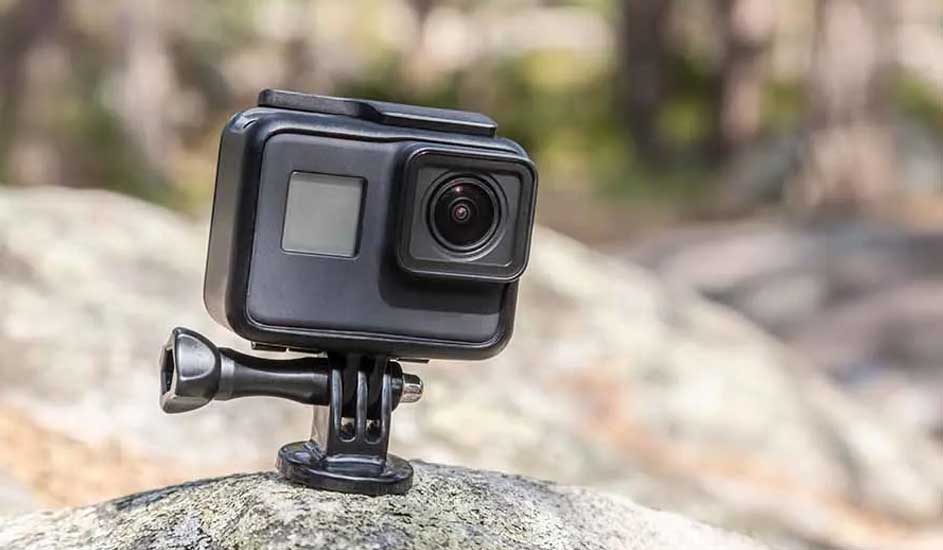 Une caméra noire est fixée sur un rocher gris. L'arrière-plan est flou avec des arbres.