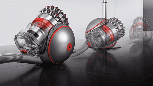 Twee grijze Dyson stofzuigers met rode accenten staan op een donkere, glanzende vloer.