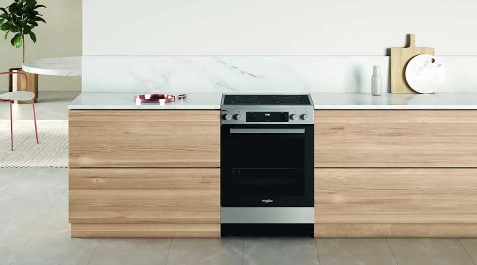 Four électrique noir et argenté intégré dans une cuisine moderne avec des armoires en bois clair.