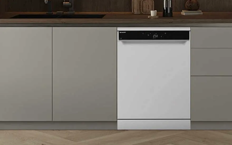 A white freestanding dishwasher is seamlessly built into light kitchen cabinets, featuring a wooden countertop and minimalist style.
