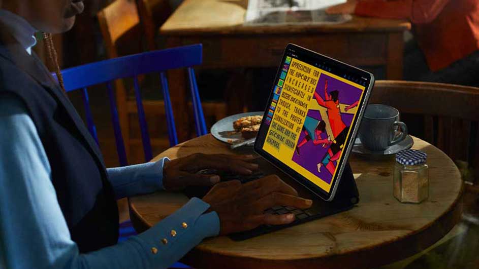 Une tablette affiche un texte coloré sur une table en bois avec une tasse, un bocal et une assiette.